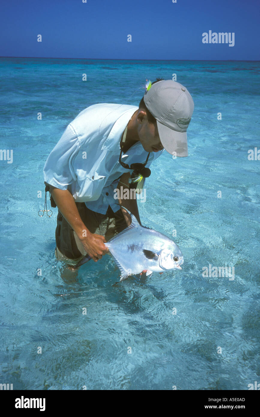 Fly fisherman holding permit fish caught while fishing in southern Belize Central America Caribbean Stock Photo