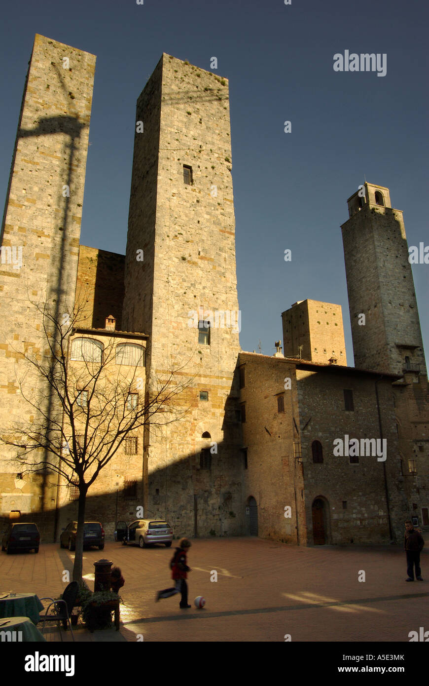 Towers of San Gimignano Tuscany boy kicks a soccer ball in the piazza vertical Stock Photo