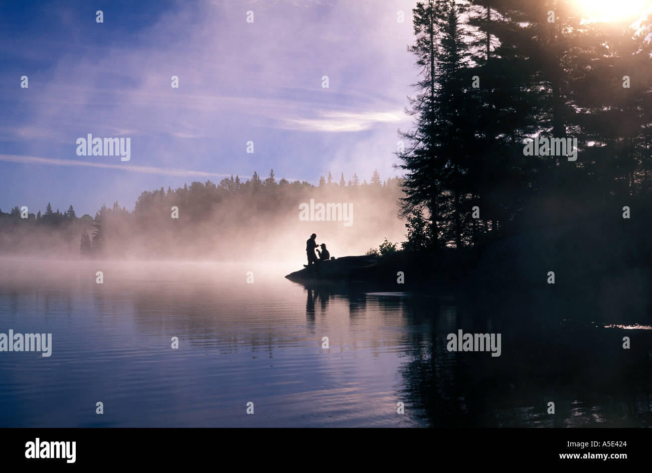 Canada, Ontario, Algonquin Provincial Park,Couple having a morning coffee enjoying the view of mist and lake at sunrise Stock Photo