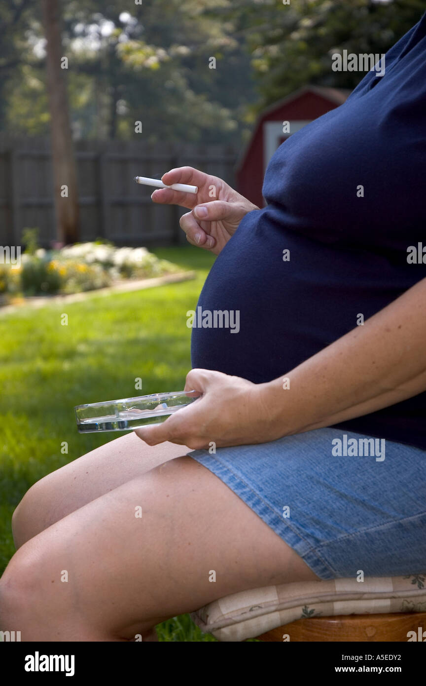 close up vertical of pregnant caucasian woman smoking cigarette, outdoors Stock Photo