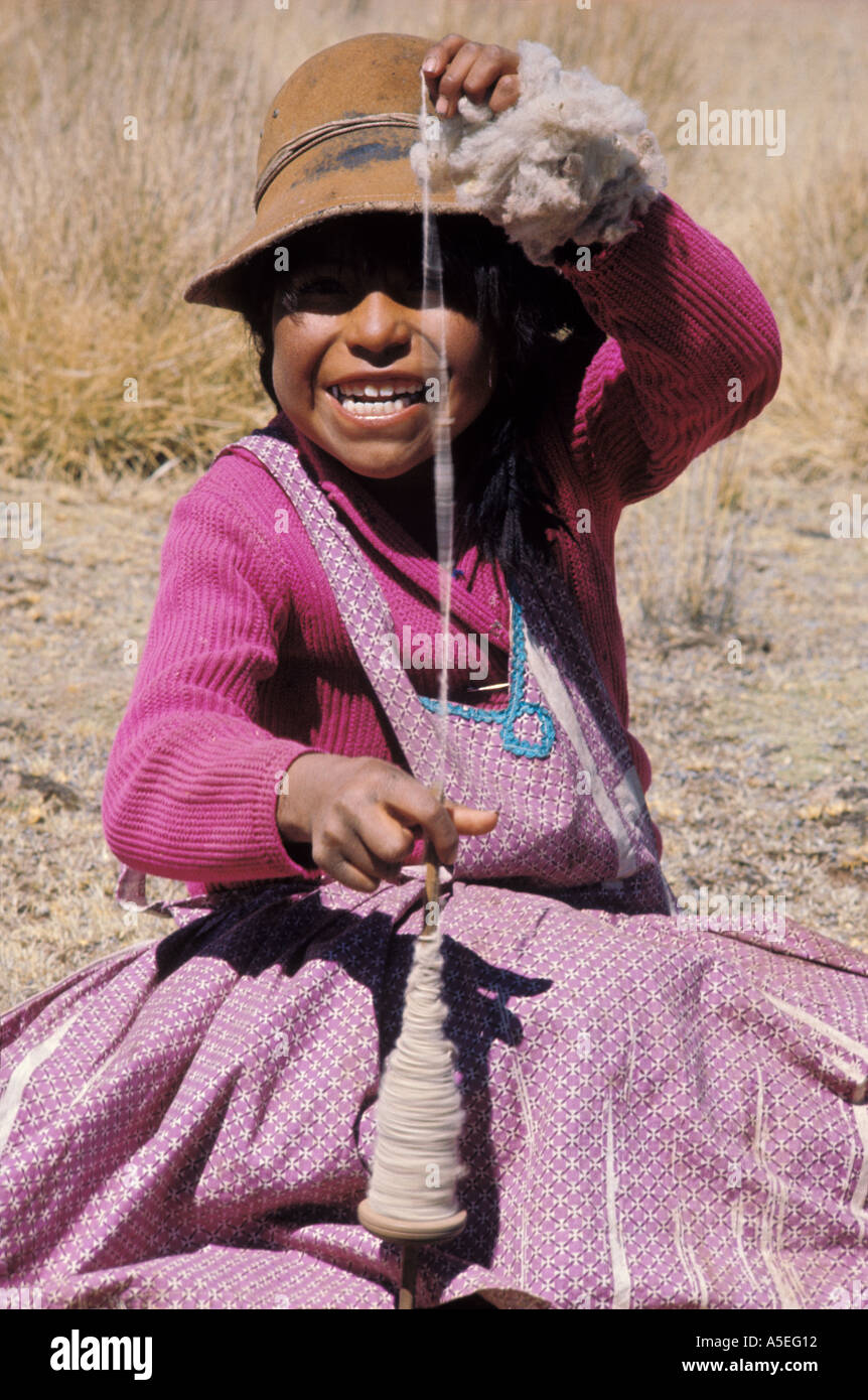 Bolivia Aymara girl spins llama wool by hand on the Altiplano in Bolivia Stock Photo