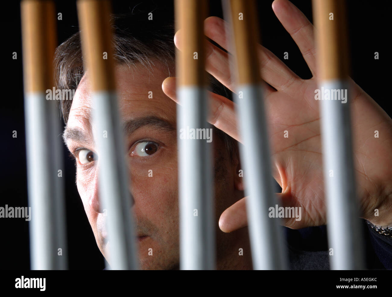 Smoker trapped behind the prison bars of addiction to nicotine Stock Photo