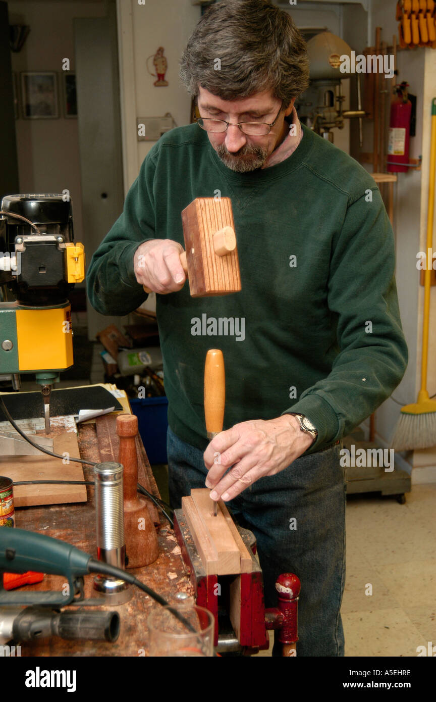 P12 119 Woodworker uses wooden hammer to knock out excess wood Stock Photo