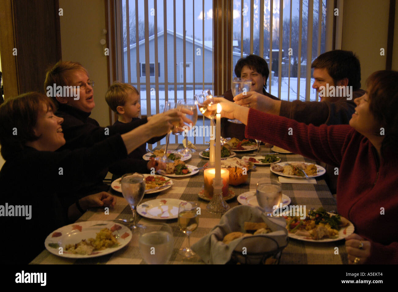 Caucasian family raises (wine) glasses in a toast of cheer during dining on thanksgiving Stock Photo