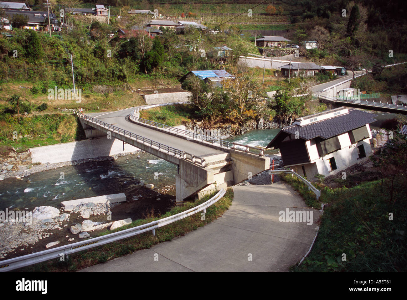 Damaged road leading to bridge and the building has fallen over due to being under cut by the river. Shiiba, Kyushu, Japan. Stock Photo