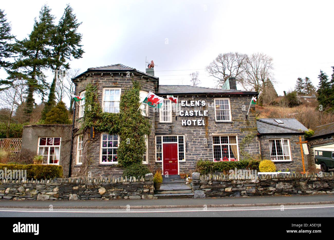 Elens Castle Hotel with red dragon flags flying outside at Dolwyddelan Gwynedd North Wales UK Stock Photo