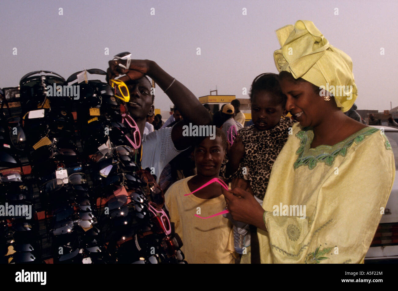 Woman in traditional clothing shopping for sunglasses from market stall, Nouakchott,  Mauritania, Africa Stock Photo