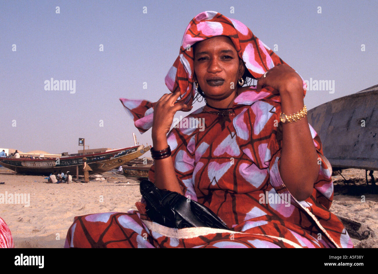 Mauritanian woman in colourful traditional clothing sitting on beach, Nouakchott, Mauritania, Africa Stock Photo
