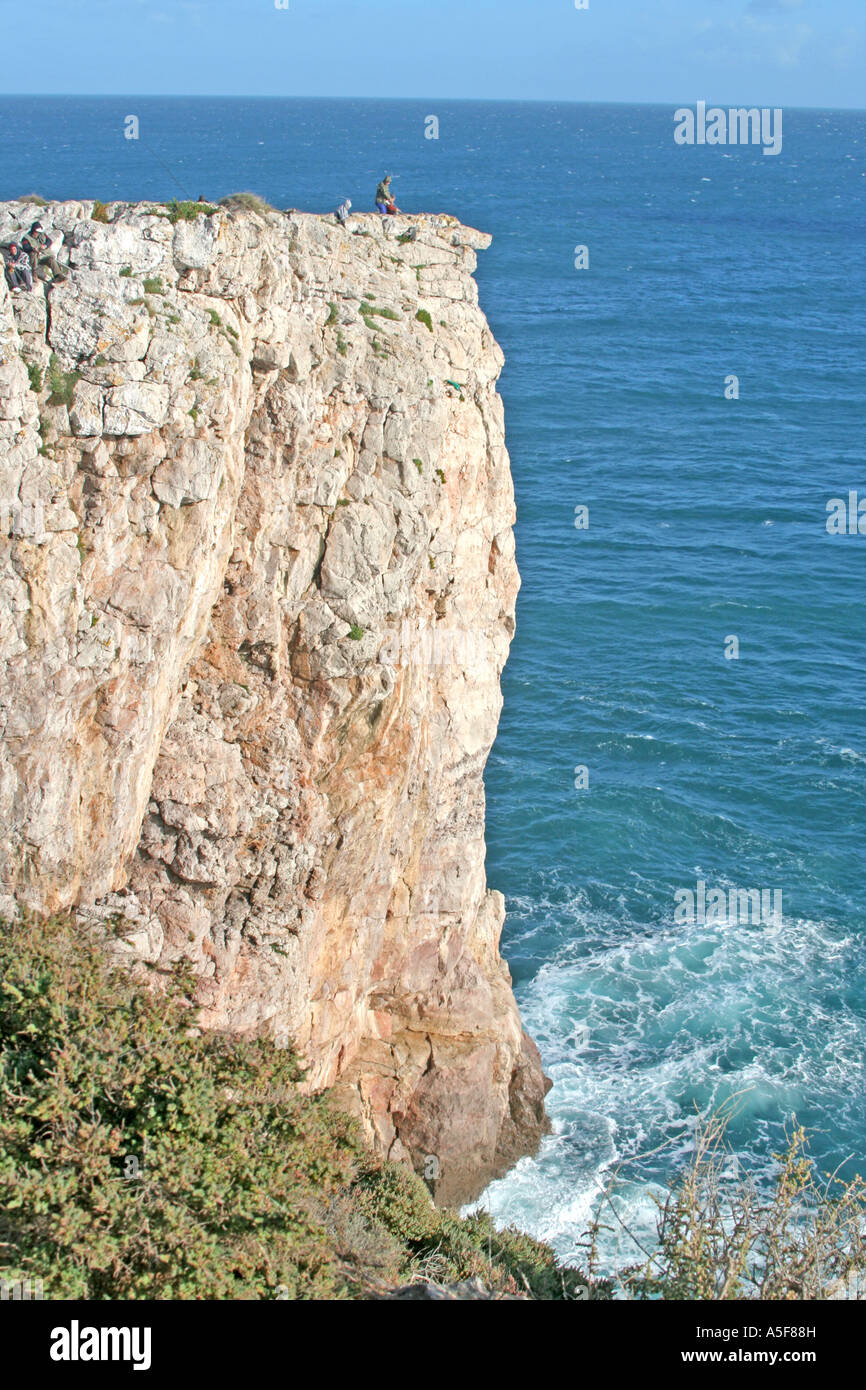 high cliffs within the Fortress of Sagres fishermen on top in the far distance Algarve Portugal Stock Photo