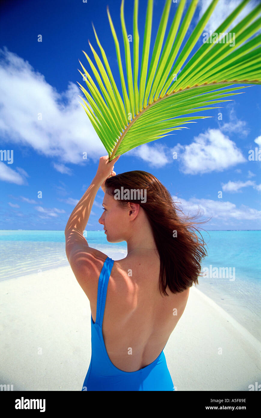 Woman holding palm frond above her head for shade in the Cook Islands South Pacific Stock Photo