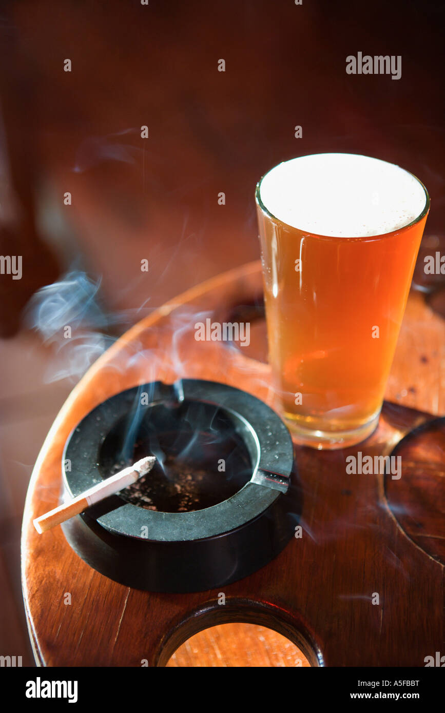 Full beer glass and cigarette with smoke rising in nightclub Stock ...