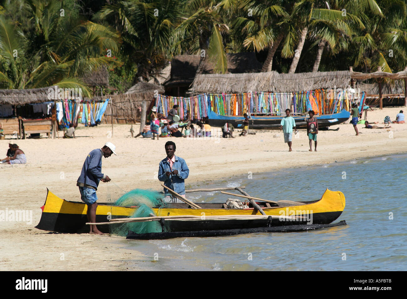A boat on a Madagascar beach, Fisherman mending net in Ifaty, near Toliara ( Tulear ) Stock Photo