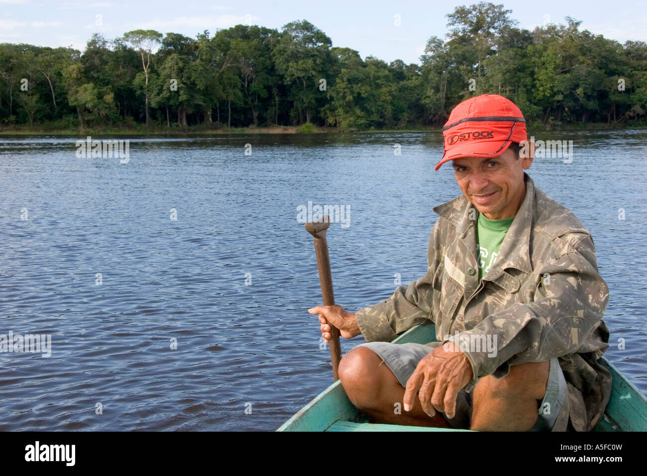 Brazilian man in a dugout canoe on the Arasa River in the Amazon jungle near Manaus Brazil Stock Photo