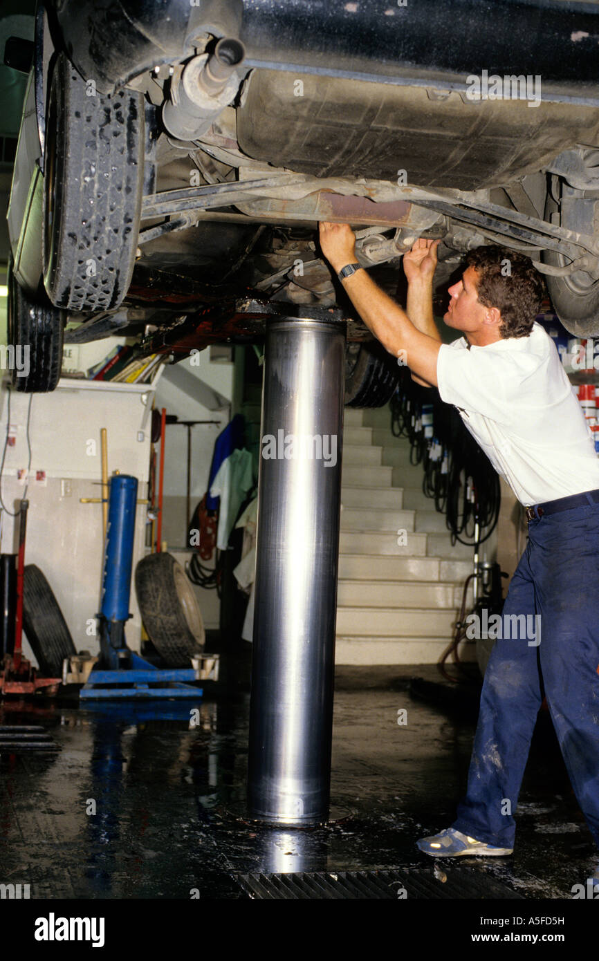 An auto mechanic working under a car on a hydraulic lift Stock Photo