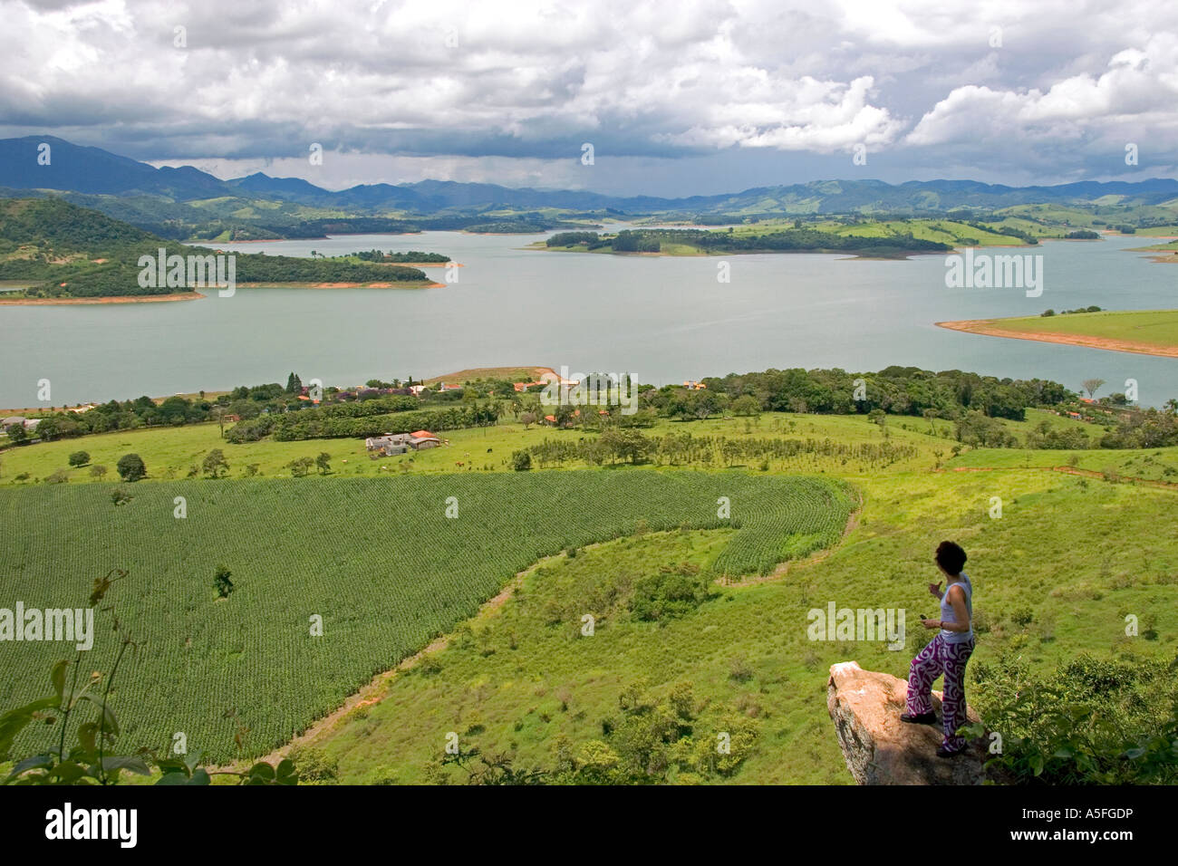 Woman standing on a rock overlooking a reservoir and the countryside near Sao Paulo Brazil MR Stock Photo