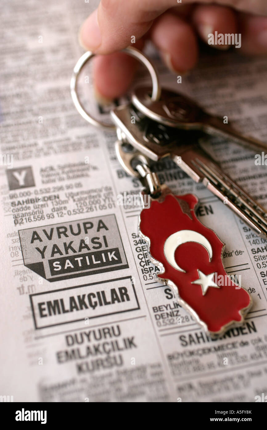 HAND HOLDING KEYS AND REAL ESTATE LISTINGS IN NEWSPAPER WITH TURKISH