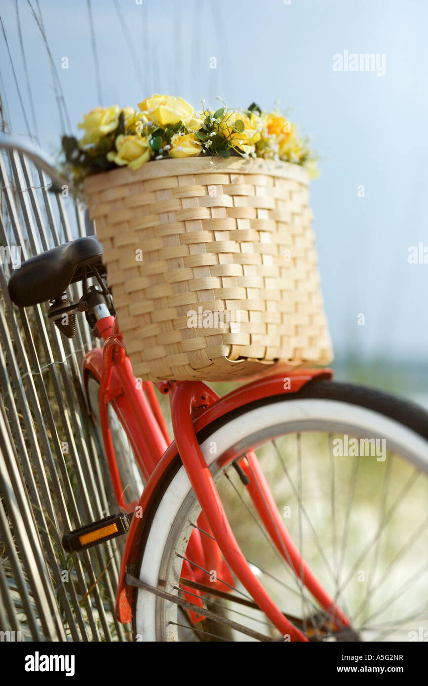 Red vintage bicycle with basket and flowers leaning against wooden