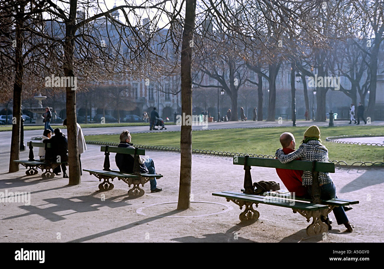 People enjoying the sun on a winter morning in the square of the Place des Vosges in Paris Stock Photo