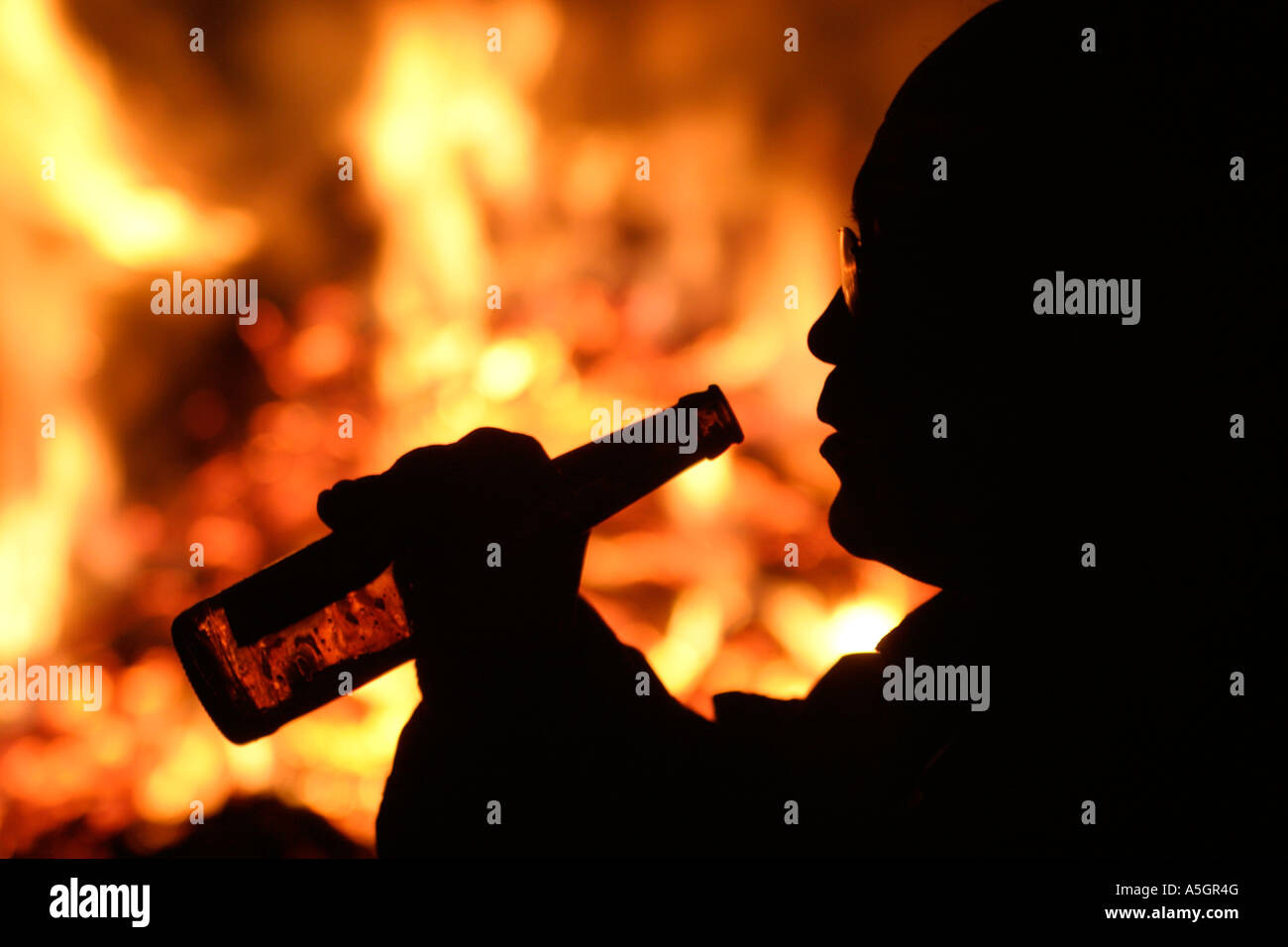 silhouette of a man drinking from a bottle of beer in front of a ...