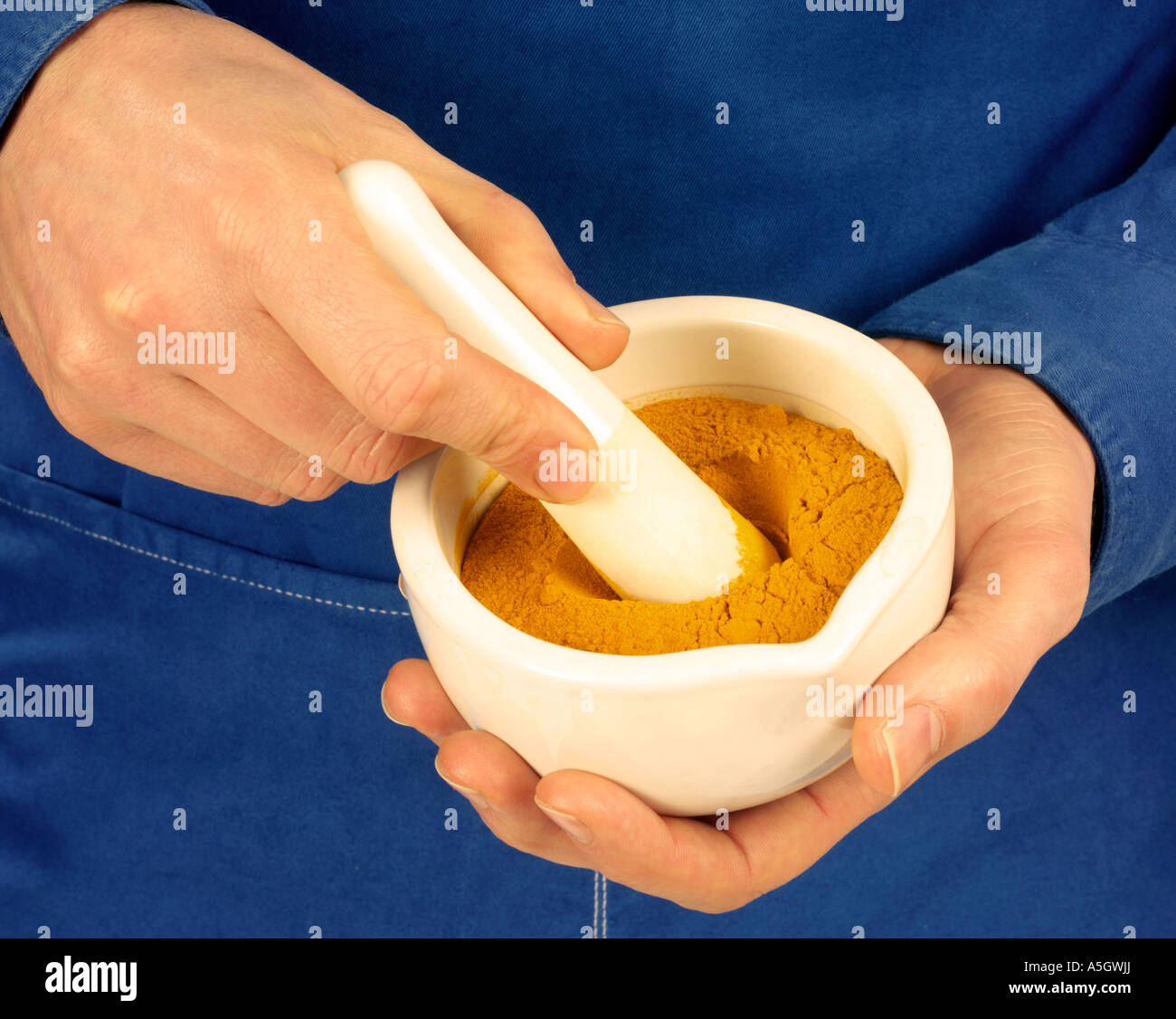 MAN GRINDING TURMERIC POWDER Stock Photo