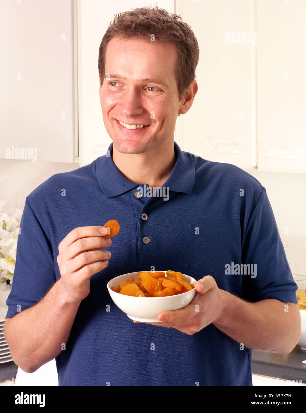 MAN IN KITCHEN EATING DRIED APRICOTS Stock Photo Alamy