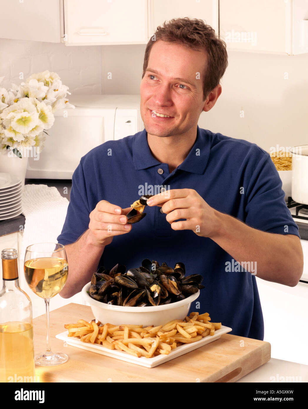 MAN EATING MUSSELS AND FRENCH FRIES OR MOULES  FRITES Stock Photo