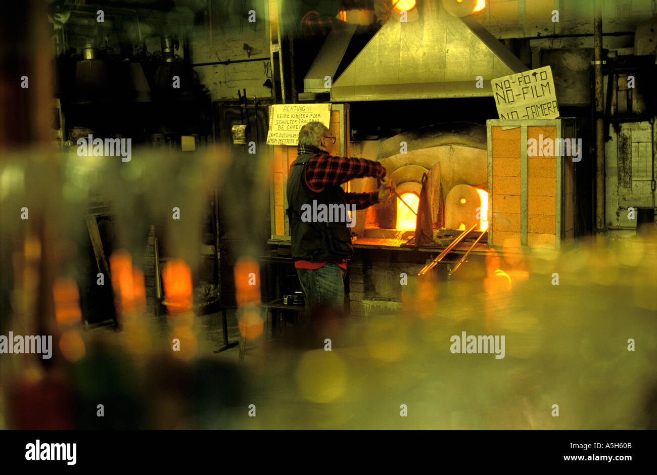 Glass blower at his furnace in Murano glass works Venice Italy Stock