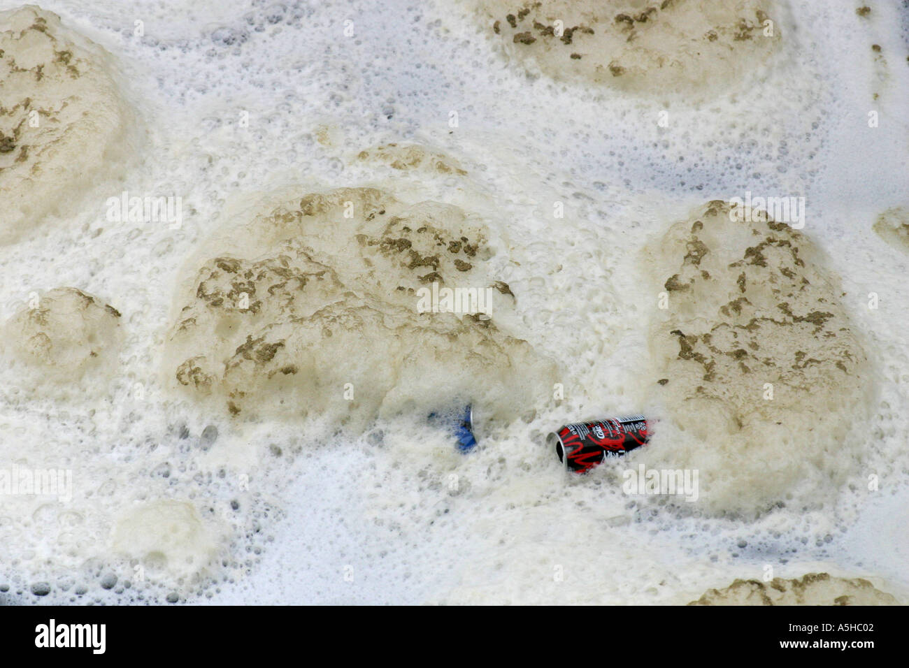 Polluted river with foam and soda cans Stock Photo