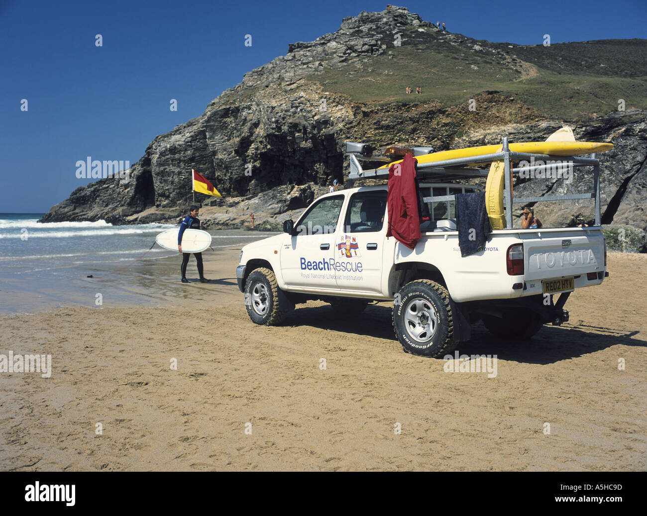 Surfer and Lifeguard patrol vehicle at Chapel Porth on the north coast of Cornwall, UK Stock Photo