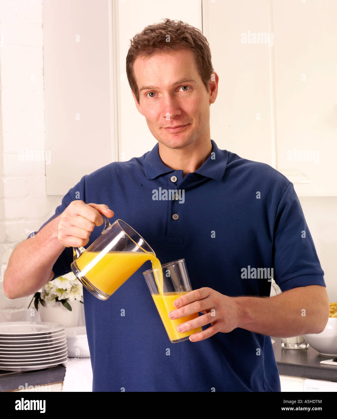 MAN IN KITCHEN POURING ORANGE JUICE Stock Photo - Alamy