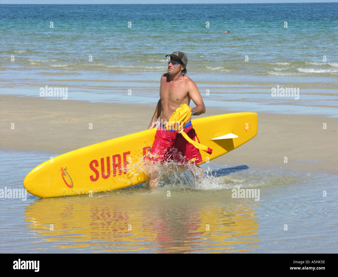 Surf lifesaver with surfboard walking back to shore Stock Photo