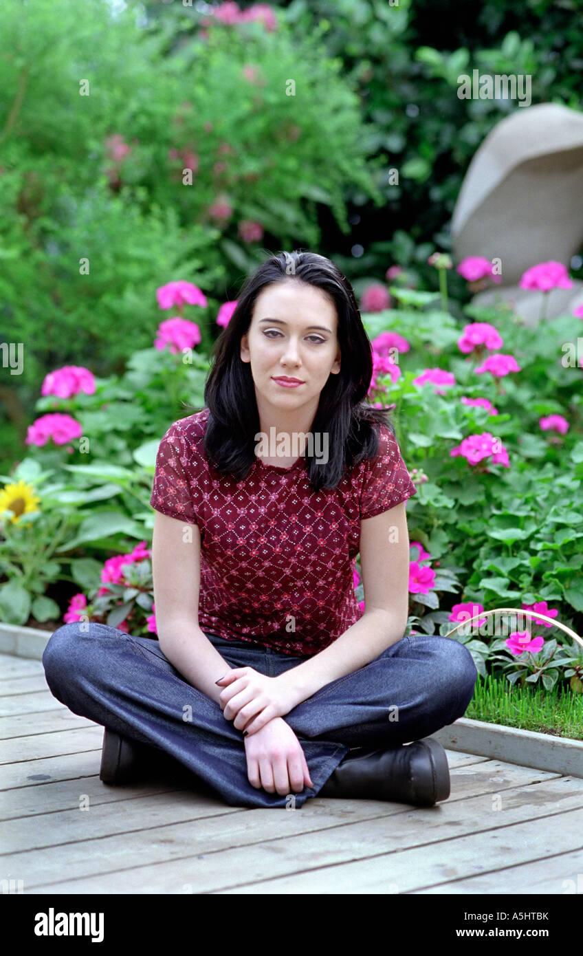 A young girl sitting in a garden with flowers Stock Photo - Alamy