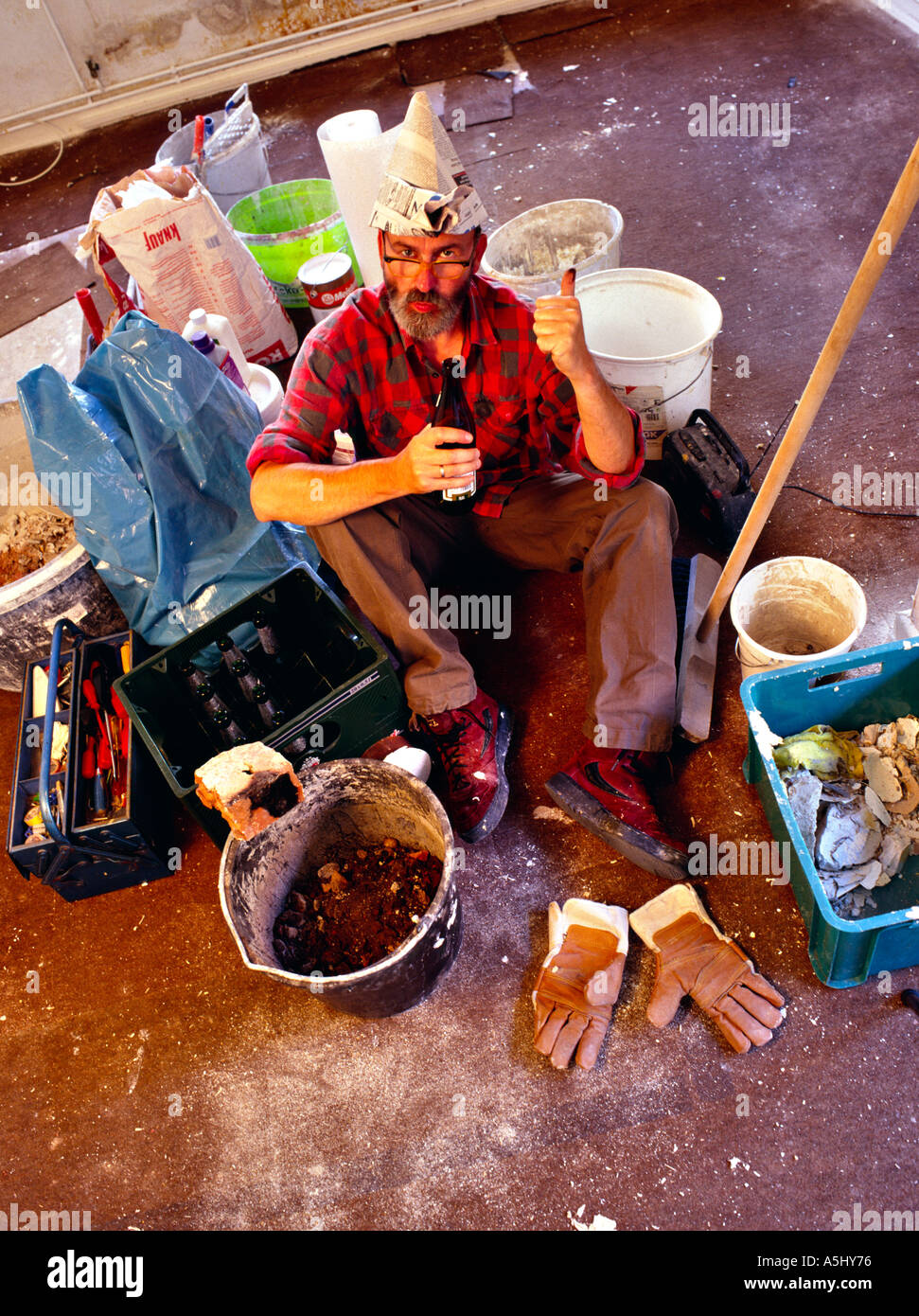 MR PR handyman do it yourselfer renovating a flat having a break and drinking a beer in middle of his tools and colour buckets Stock Photo