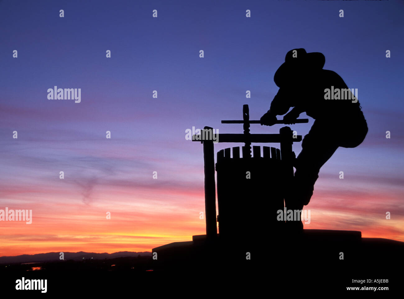 The iconic 15 foot high Grape Crusher Statue on Highway 29 silhouetted by a colorful sunset sky in Napa Valley Wine Country in Northern California. Stock Photo