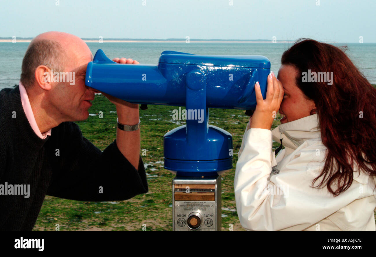 MR lovers walking at seacoast looking together in a telescope Stock Photo