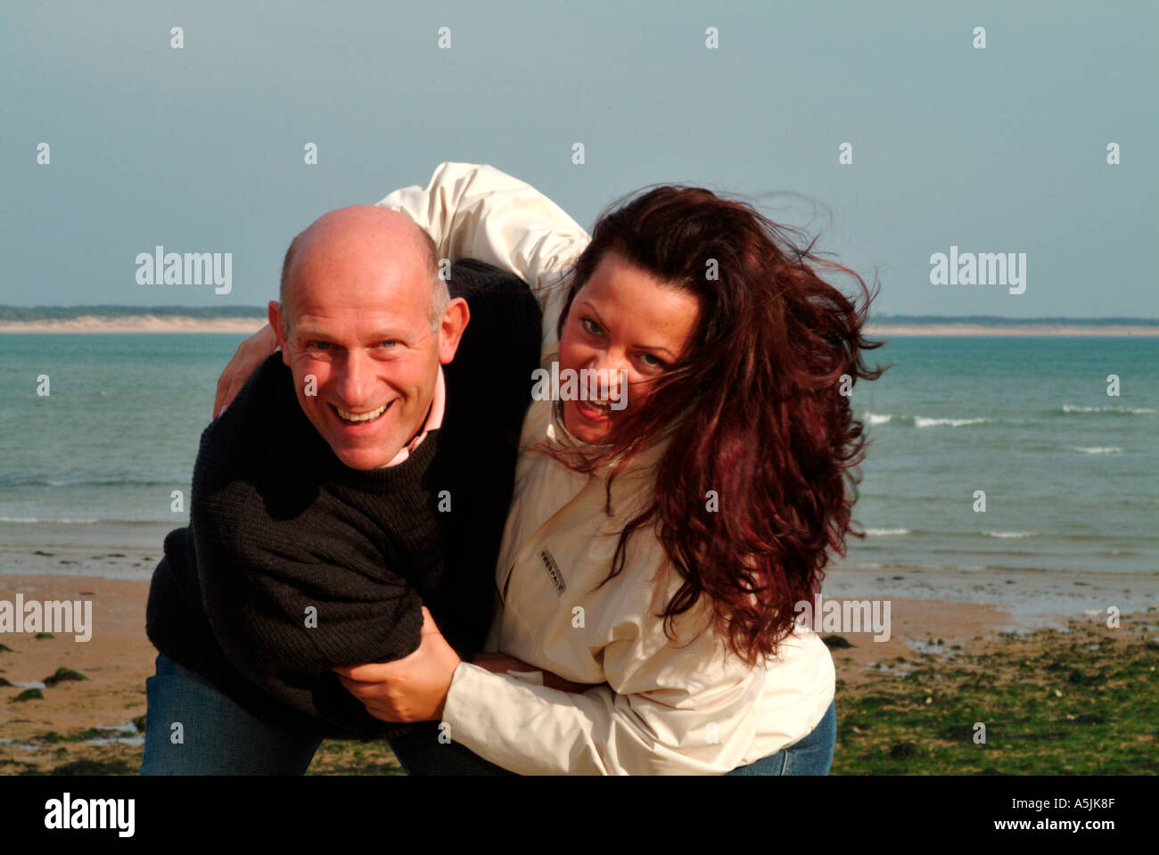 MR lovers walking at seacoast in joyful embracement Stock Photo