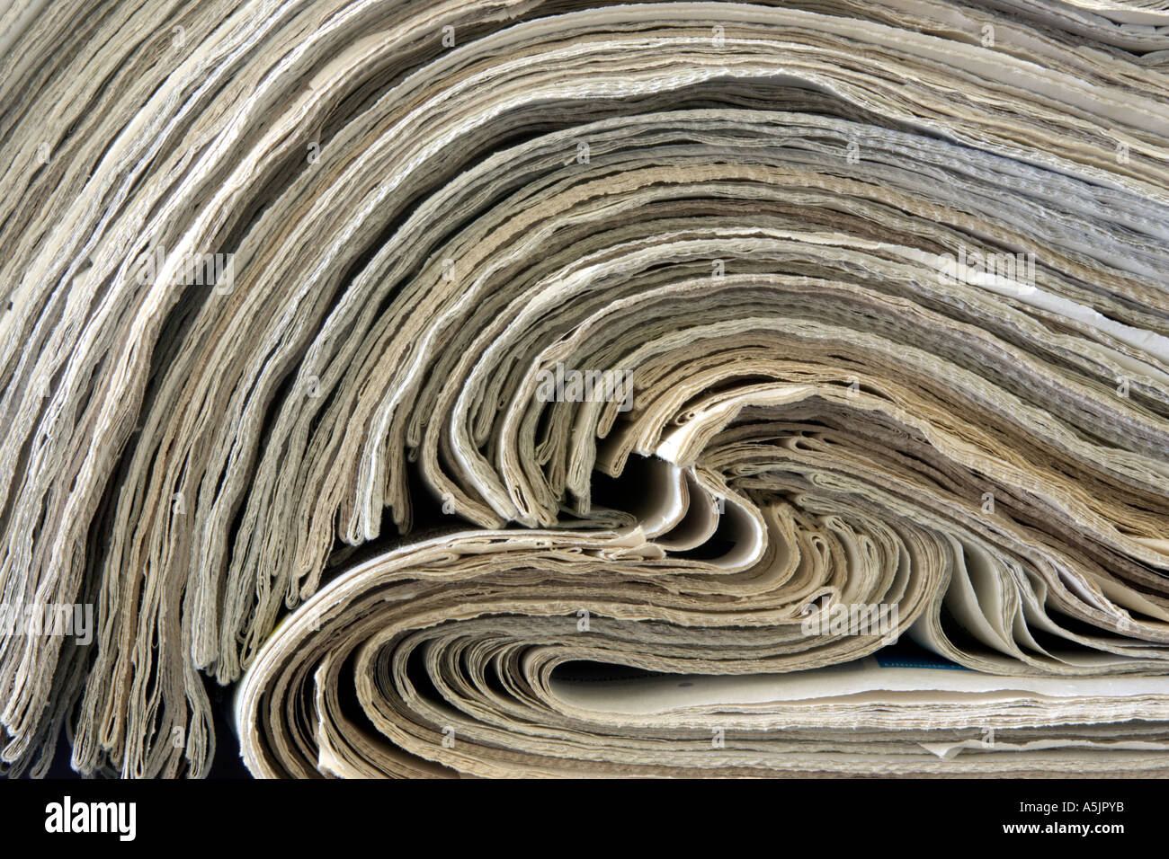 stack of old newspapers rolled back on themselves Stock Photo