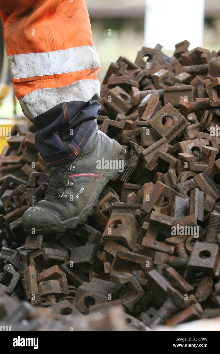 A worker with hard-toed step in scrap metall Stock Photo