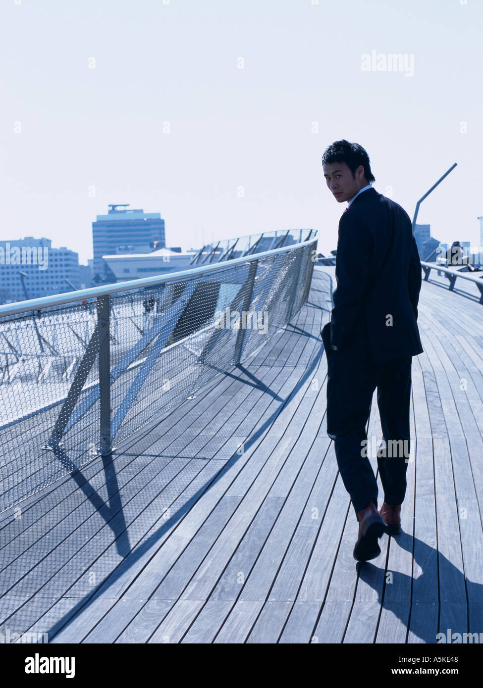 Asian Man walking on a bridge Stock Photo - Alamy
