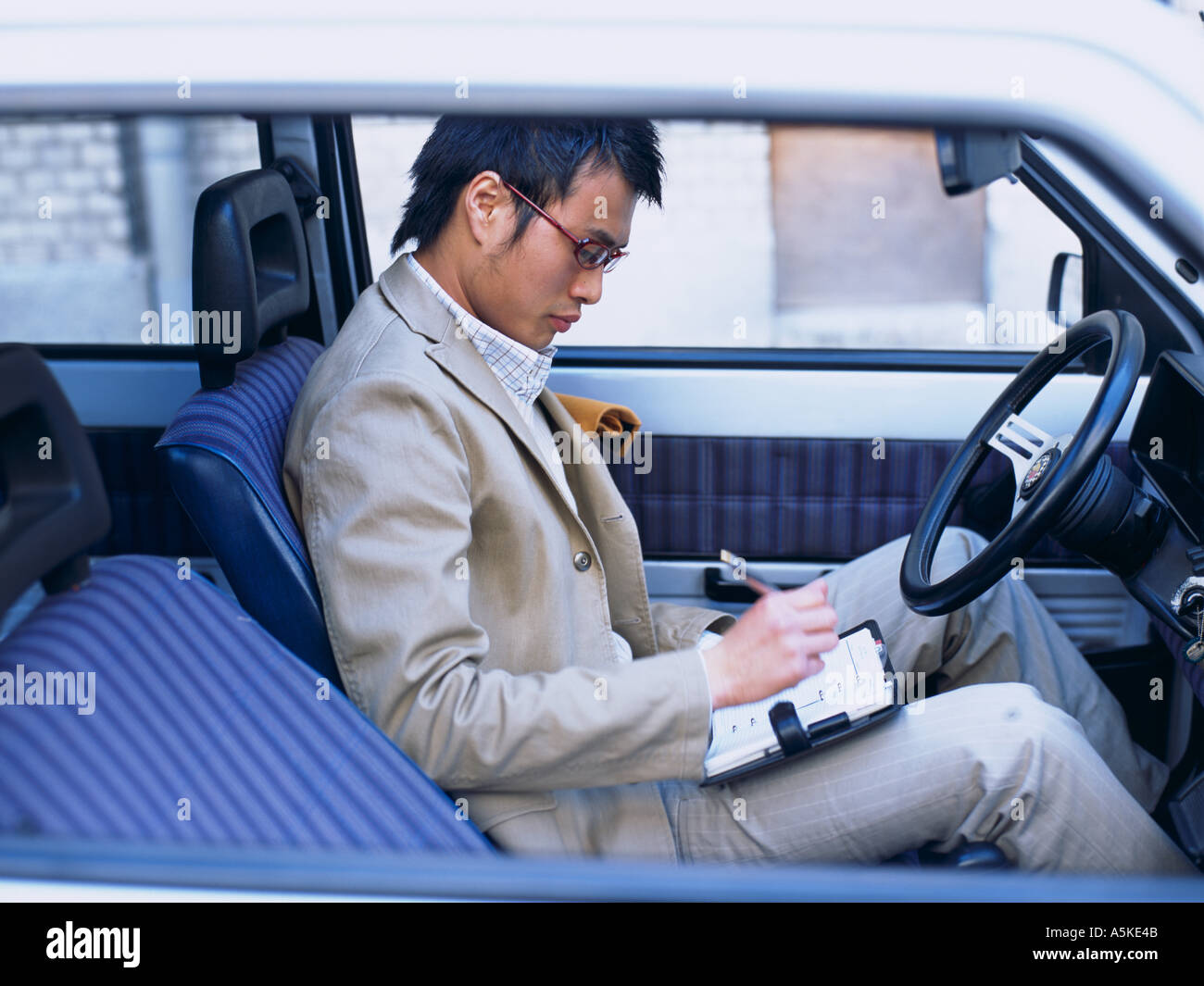 Asian Man making notes in a car Stock Photo