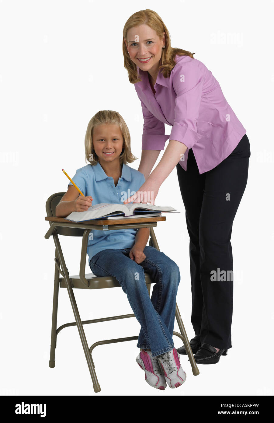 Female teacher helping student at desk Stock Photo