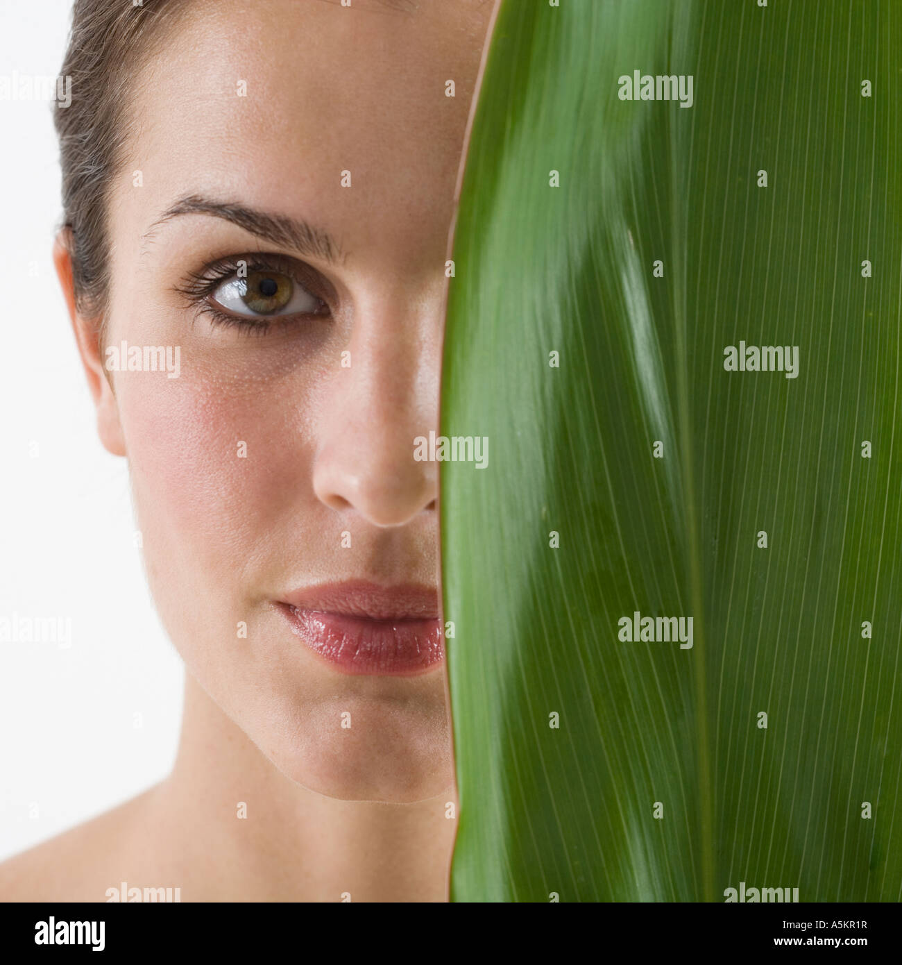 Woman holding leaf over half of face Stock Photo - Alamy