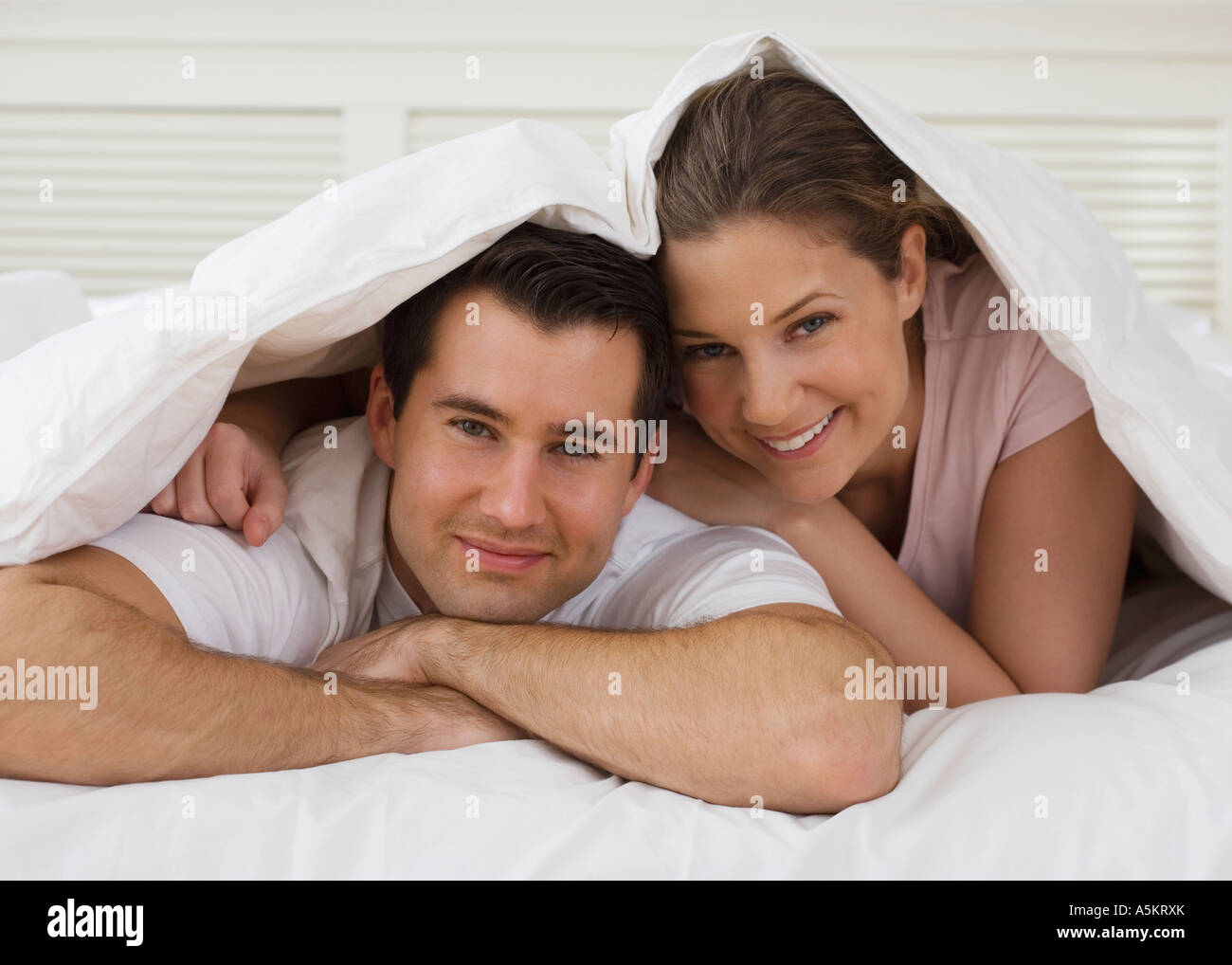 Portrait of couple under bed covers Stock Photo Alamy