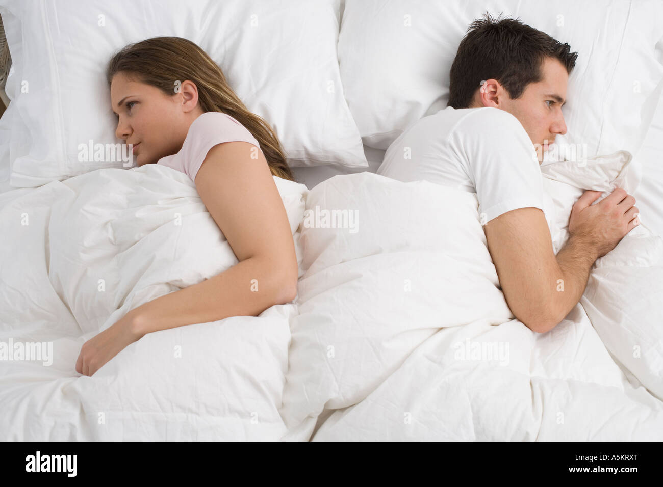 Angry couple laying in bed Stock Photo