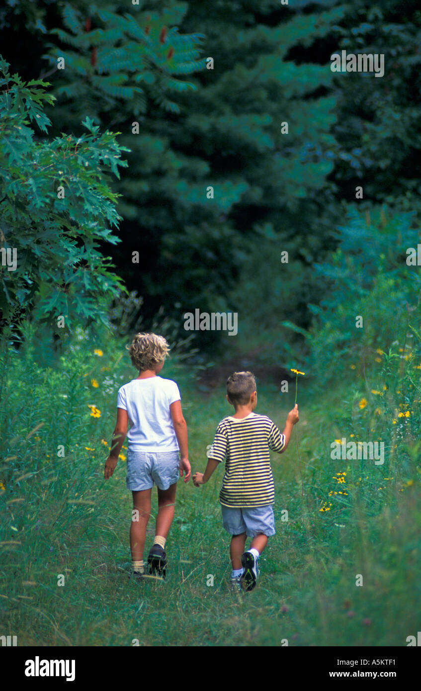 Brother and sister on meadow trail into forest Stock Photo - Alamy