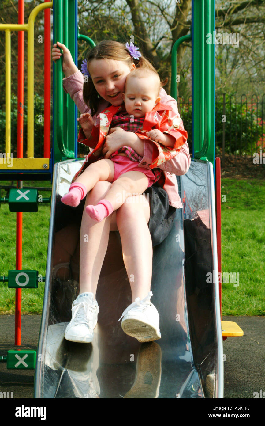 two girls on a slide in a playground Stock Photo - Alamy
