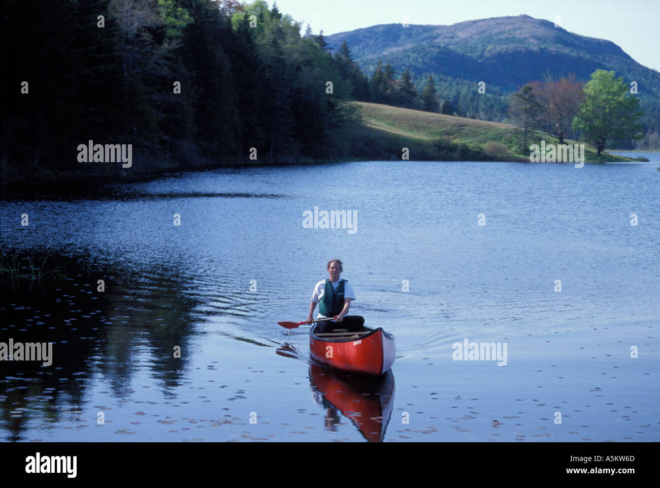 Woman canoeing alone on Little Long Pond Maine Stock Photo