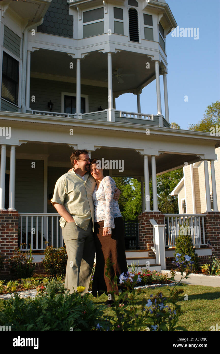 A married couple expecting their first child stand happily in front of