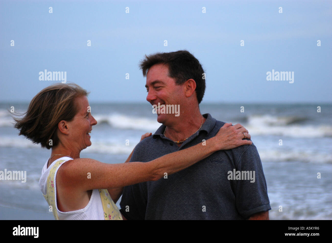 A woman wraps her arms around her husband joyfully as they walk along