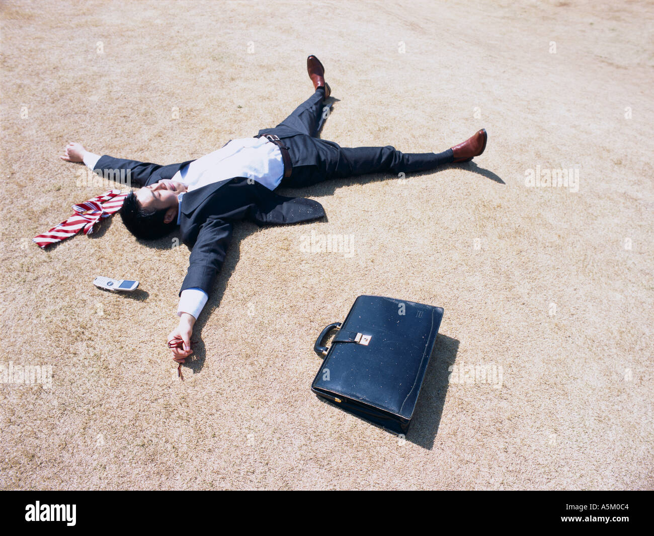 Asian Businessman lying flat on the ground Stock Photo